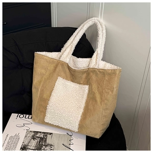 Detailed close-up of brown suede and white faux fur patchwork tote bag on a black sofa