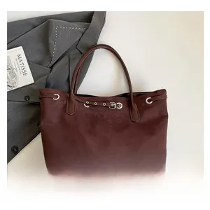 Macro detail of dark suede tote bag with decorative buckle and silver eyelets