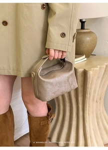 Detail of vintage champagne gold handbag with textured finish and top handle for women
