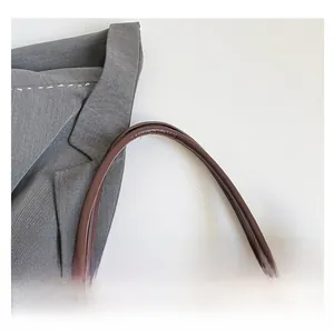 Close-up of the smooth rounded handle and sturdy stitching on a dark brown tote bag