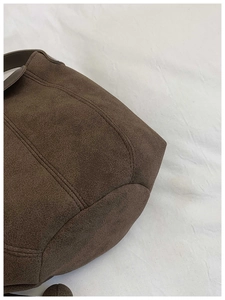 Detailed view of dark brown frosted leather bucket bag featuring reinforced stitching