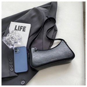 Detailed close-up of a black baguette bag with vintage leather texture and zipper closure