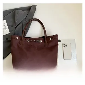 Close-up of large burgundy suede tote bag showing leather strap and metal ring details