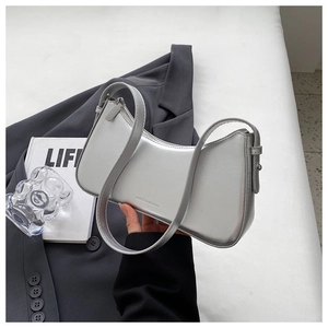Detail of silver metallic hobo bag featuring logo text and adjustable shoulder strap