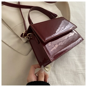 Détail du sac à main en cuir verni rouge vin avec finition brillante et boucle dorée