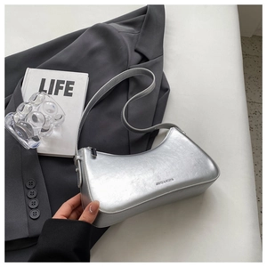 Close-up of a metallic silver baguette bag with liquid metal texture and adjustable strap