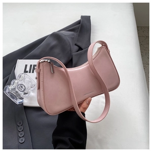 Close-up of pink leather baguette bag on grey blazer with fashion magazine props