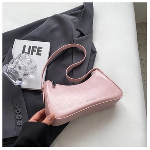 Detail of light pink leather baguette bag with embossed logo on a lifestyle background