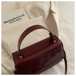 Vue macro d'un sac à main en cuir verni rouge foncé avec finition miroir et design épuré