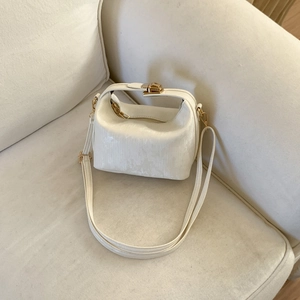 Elegant white crossbody pillow bag with gold clasp shown on a sofa background