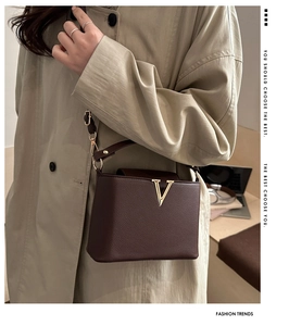 Dettaglio borsa in pelle testa di moro con fibbia a V dorata su trench color kaki