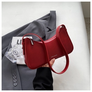 Macro shot of red leather baguette bag with silver brand logo and zip closure detail