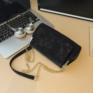 Chic black matte tote bag with gold chain strap shown on a minimalist desktop workspace
