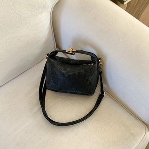 Chic black pillow bag with textured pattern, gold clasp, and adjustable shoulder strap