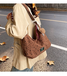 Détail du sac hobo en velours côtelé marron avec motifs cœurs et breloque ours en peluche