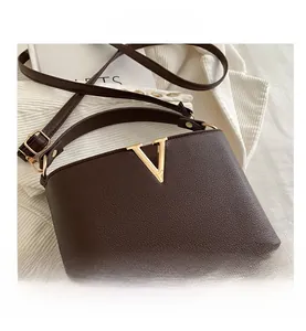 Dettaglio borsa in pelle marrone scuro con trama litchi e fibbia a V in metallo dorato