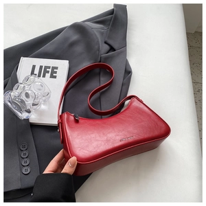 Detail of red PU leather half-moon shoulder bag with metal zipper and brand logo