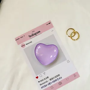 Violetter herzförmiger Glaskristall-Handyhalter mit goldenen Ringen auf Stoff