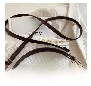 Dettaglio ravvicinato della borsa in pelle litchi marrone scuro con logo a V dorato lucido