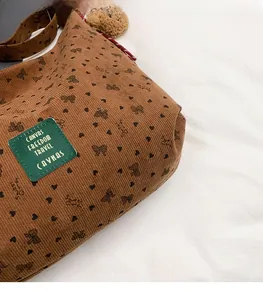 Détail du sac cabas en velours côtelé marron avec motifs de cœurs et texture premium