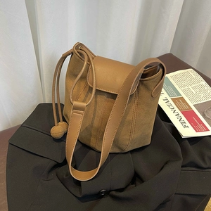 Minimalist caramel brown bucket bag in suede and leather finish on a black blazer