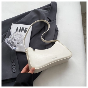 Detail view of white half-moon underarm bag with zipper and branded texture