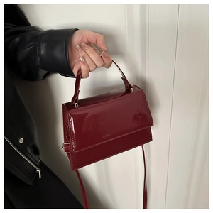 Détails d'un mini sac en cuir verni bordeaux foncé avec poignée et bandoulière amovible