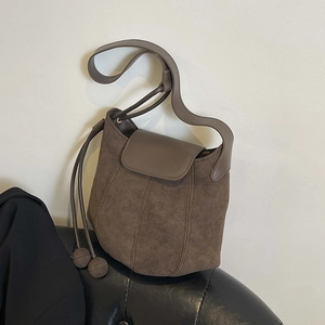 Minimalist brown suede and leather bucket bag featuring decorative side drawstrings