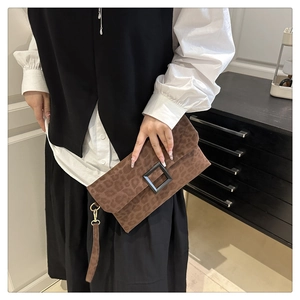 Close-up of leopard print envelope clutch featuring a black buckle and wrist strap