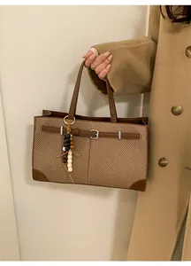 Detail of vintage plaid tote bag featuring dark brown leather trim and wooden bead charm