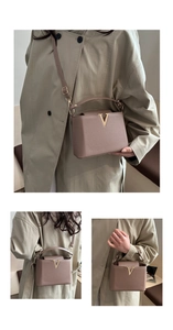 Detailed view of dust pink pebbled leather bag with gold V-shaped metal buckle and strap