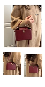 Detailed close-up of burgundy textured leather handbag featuring iconic gold V buckle