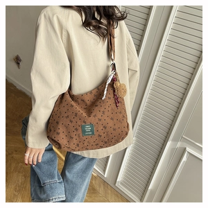 Détail d'un sac à bandoulière en toile marron avec motifs cœurs et pompon doux