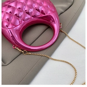Close-up of bright pink metallic mini bag with quilted pattern and gold chain strap