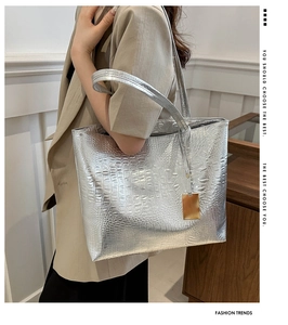 Sac fourre-tout argenté à texture crocodile avec pendentif doré porté à l'épaule