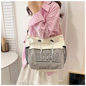 Detail of off-white canvas tote with grey mesh pocket and black WIRA logo on adjustable strap