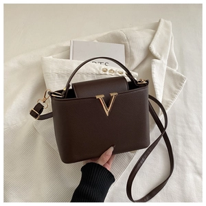 Close-up of dark brown lychee texture leather handbag with large gold V-buckle detail