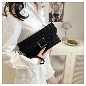 Close-up of leopard print clutch bag with matte black buckle and wristlet strap