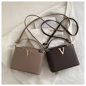 Detail of coffee and brown lychee grain bags with gold V-shaped metal buckle accents