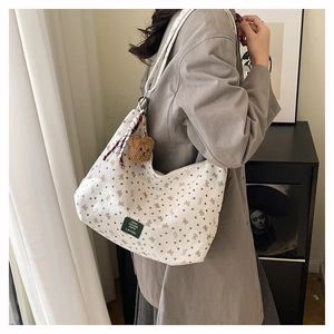 Détail du sac cabas en toile avec motif nœuds, étiquette verte et pendentif ours brun