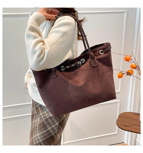 Detail van de donkerbruine matte draagtas met slanke riemen en metalen oogjesaccenten
