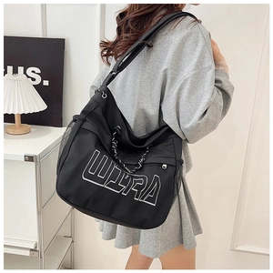 Detail of black canvas tote bag showing white Ultra embroidery and side mesh pocket