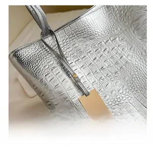 Détail du cabas argenté avec motif crocodile, fini métallique et étiquette dorée