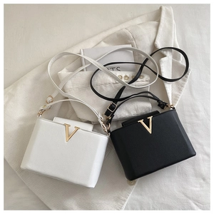 Close-up of texture leather cross-body bags with gold V buckles in white and black