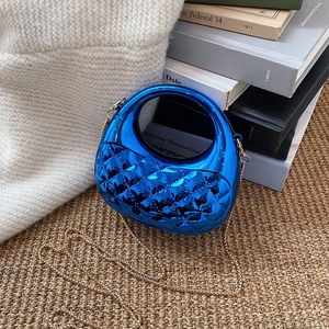 Mini acrylic quilted handbag in bright blue with gold chain strap on a woven mat