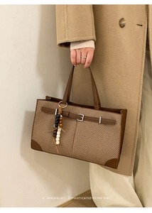 Detail of retro plaid tote bag featuring brown leather trim and wooden bead charm