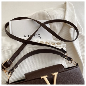 Close-up of deep brown lychee grain leather handbag with gold V-shape metal logo