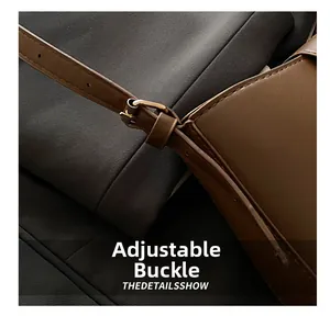 Détail de la boucle réglable en bronze sur la bandoulière en cuir marron du sac minimaliste