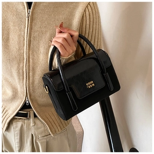 Detailed close-up of a black textured handbag with gold COIH '2DN' logo and hardware