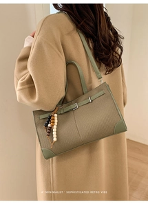 Detail of retro green woven tote bag with bead tassel and decorative leather belt strap